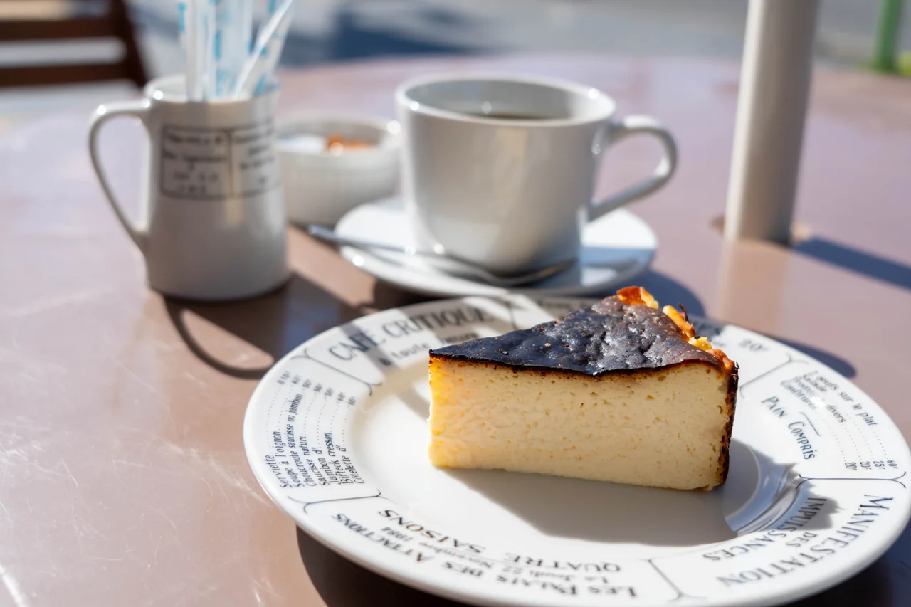 A slice of Basque cheesecake with coffee in the background