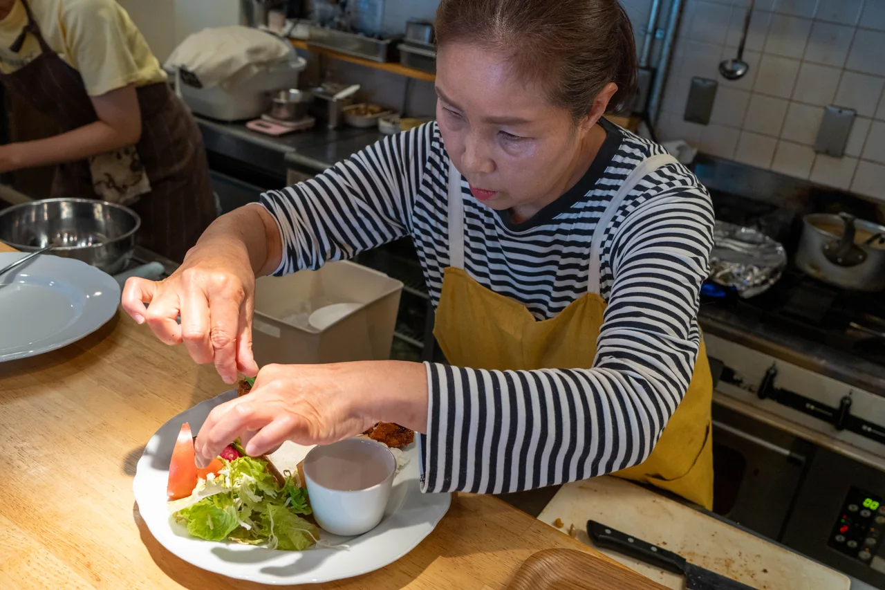 A cook carefully arranging vegetables on a plate