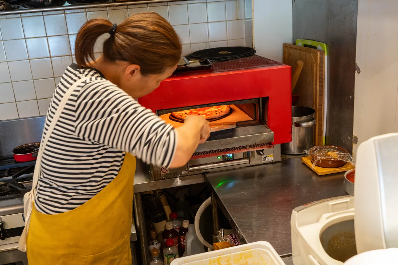 The owner checking a pizza in the oven