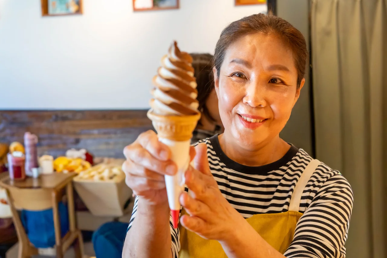 The owner smiling and holding a soft serve cone